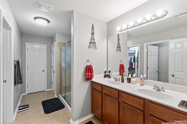 bathroom with vanity, a textured ceiling, tile patterned flooring, and a shower with door