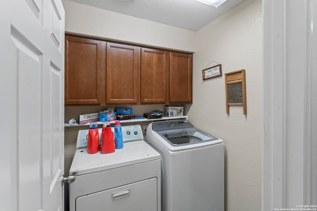 laundry area featuring cabinets, a textured ceiling, and washer and dryer