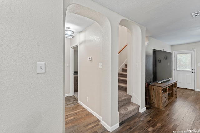 hall featuring a textured ceiling and dark wood-type flooring