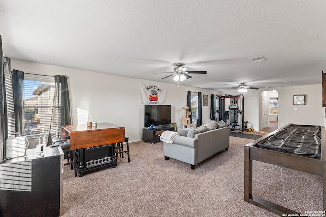 living room with ceiling fan, carpet floors, and a textured ceiling