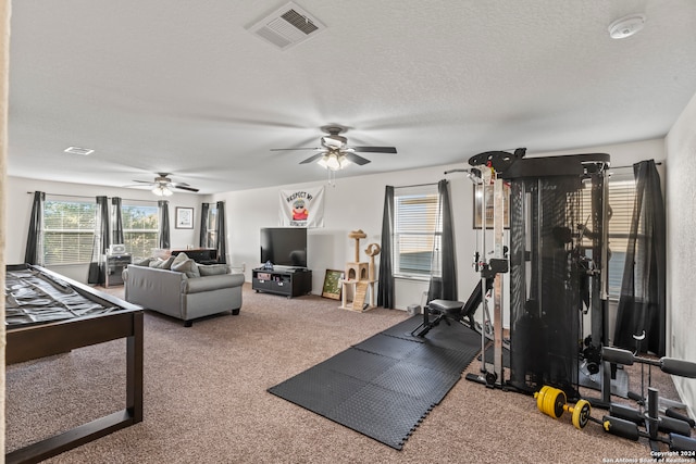 workout room featuring a textured ceiling, ceiling fan, and carpet floors