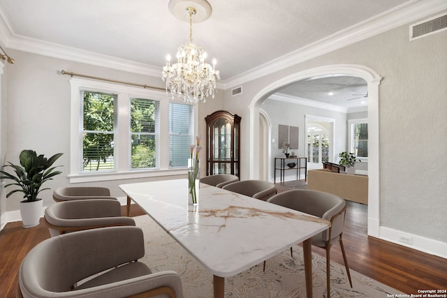 dining room with ornamental molding, ceiling fan with notable chandelier, plenty of natural light, and dark hardwood / wood-style flooring