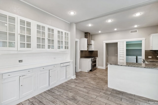 kitchen with light hardwood / wood-style floors, washing machine and dryer, white cabinetry, light stone countertops, and gas range