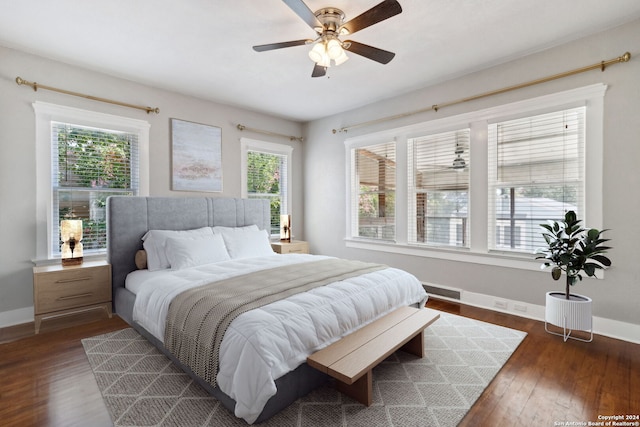 bedroom with ceiling fan, multiple windows, and dark wood-type flooring