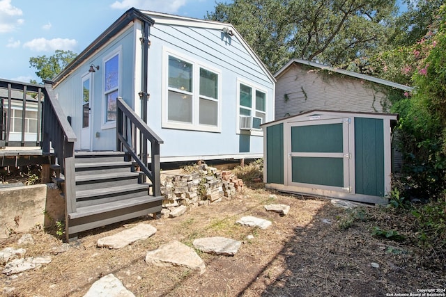 rear view of house with cooling unit and a shed