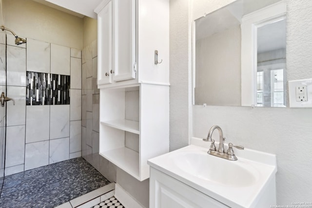 bathroom with tile patterned floors, vanity, and tiled shower