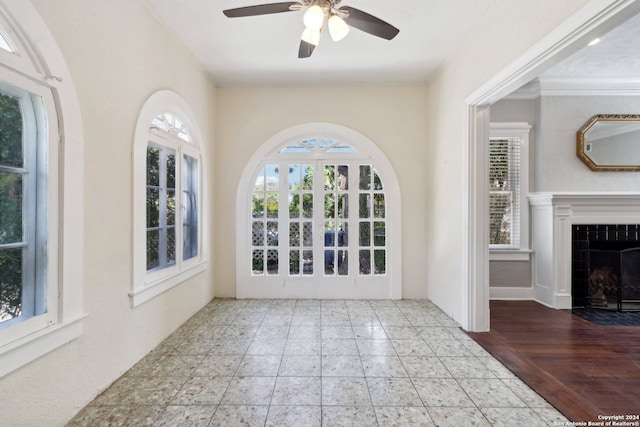 interior space featuring ornamental molding, a tiled fireplace, hardwood / wood-style floors, and ceiling fan