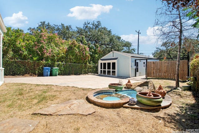 view of yard with an in ground hot tub, a patio area, and an outbuilding