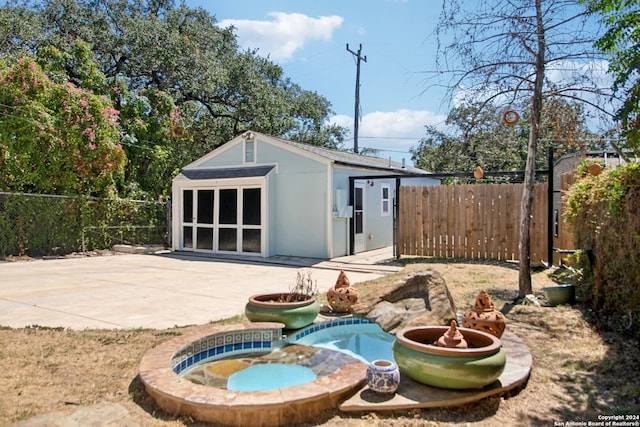 exterior space with a patio, an in ground hot tub, and an outdoor structure