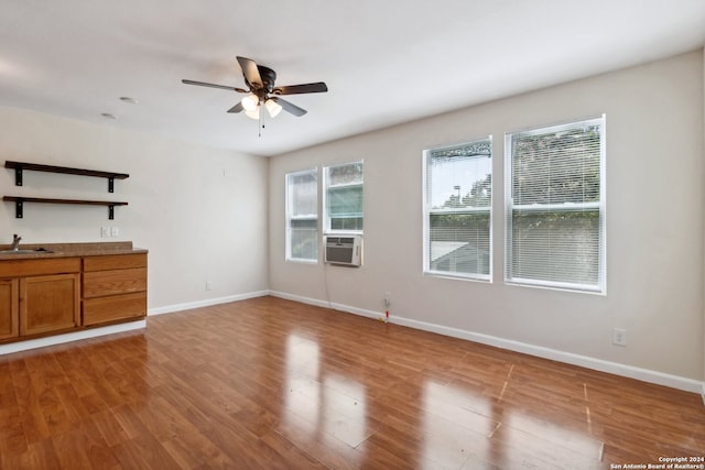 unfurnished living room featuring ceiling fan, cooling unit, light hardwood / wood-style flooring, and sink