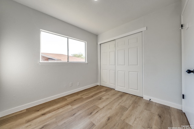 unfurnished bedroom featuring light wood-type flooring and a closet