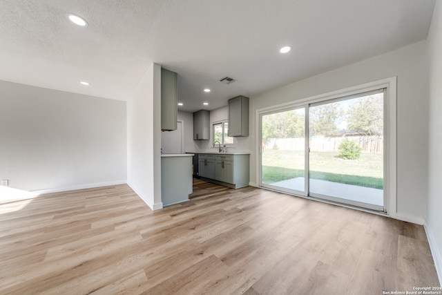 unfurnished living room featuring light hardwood / wood-style flooring, a textured ceiling, and sink