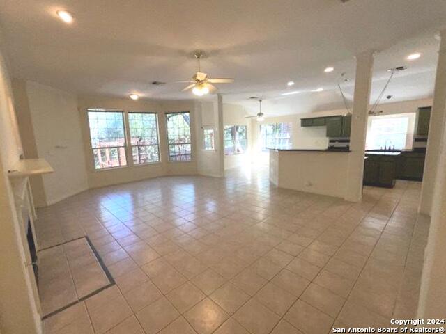 unfurnished living room featuring light tile patterned floors, a wealth of natural light, and ceiling fan