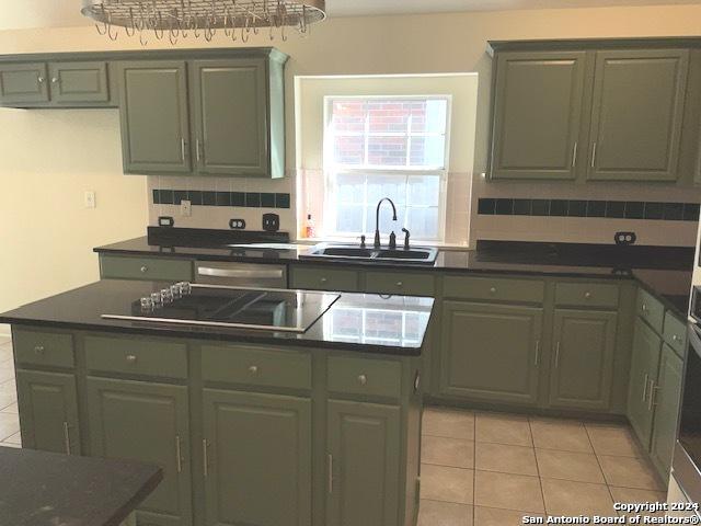 kitchen featuring sink, backsplash, light tile patterned floors, and black electric stovetop