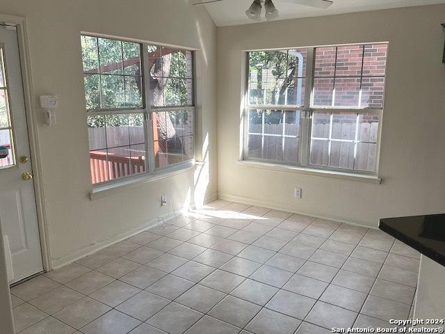 unfurnished dining area featuring light tile patterned floors and ceiling fan