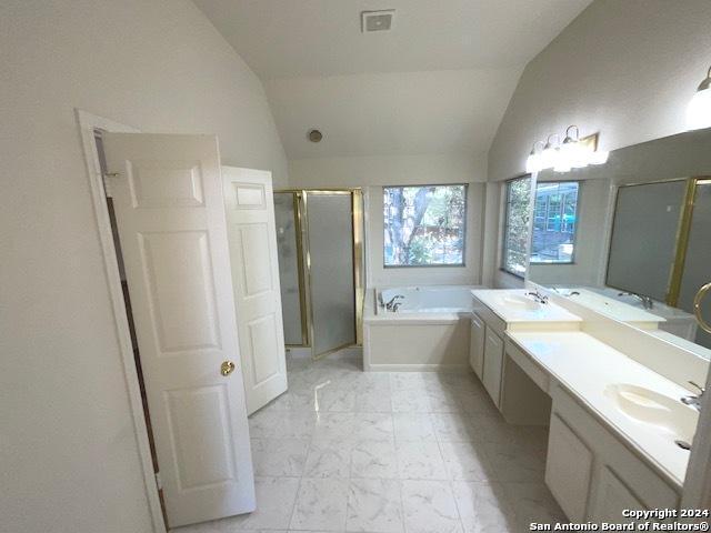 bathroom featuring independent shower and bath, vaulted ceiling, and vanity