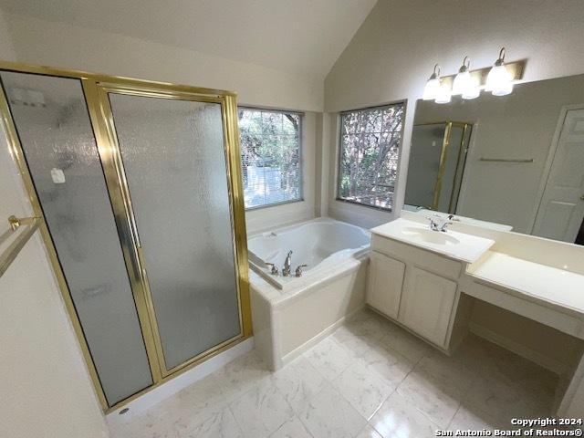 bathroom featuring independent shower and bath, vaulted ceiling, and vanity