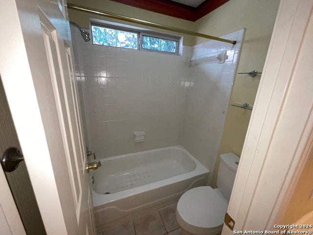 bathroom with tile patterned flooring, tiled shower / bath combo, and toilet