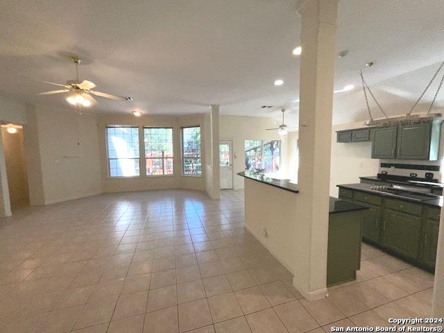 kitchen with light tile patterned floors, green cabinetry, ceiling fan, and ornate columns