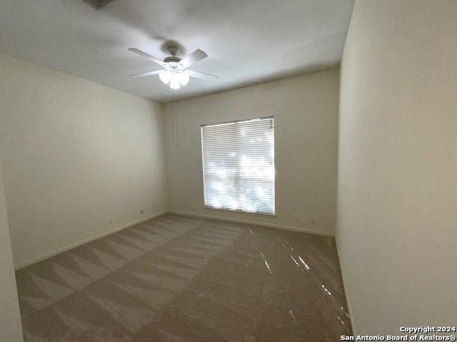 spare room featuring ceiling fan and dark carpet