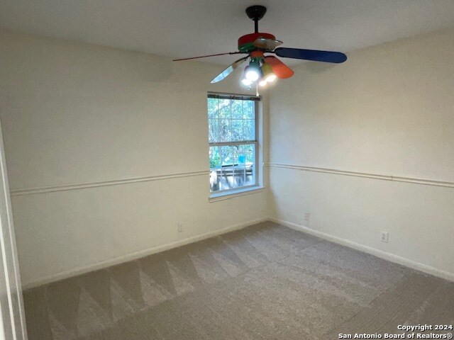 carpeted empty room featuring ceiling fan