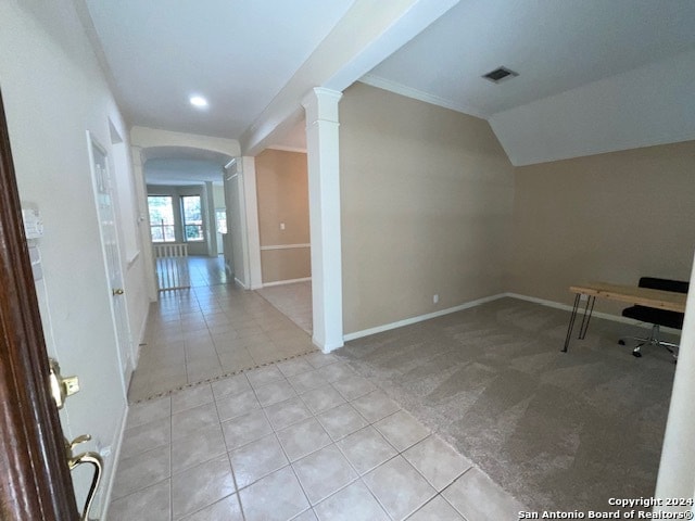 interior space featuring decorative columns, vaulted ceiling, and light colored carpet