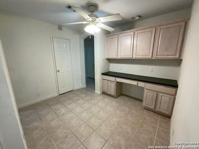 unfurnished office featuring built in desk, ceiling fan, and light tile patterned floors