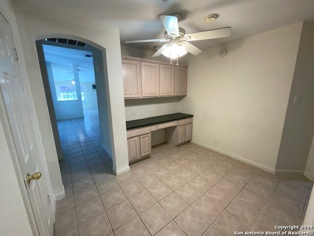 interior space with ceiling fan, built in desk, and light tile patterned floors