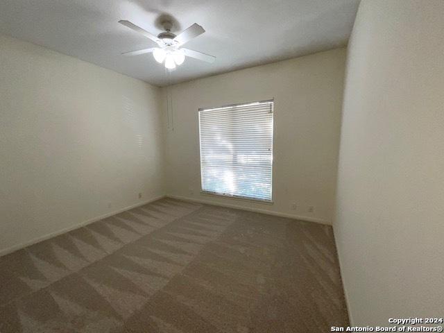 unfurnished room with dark carpet and ceiling fan