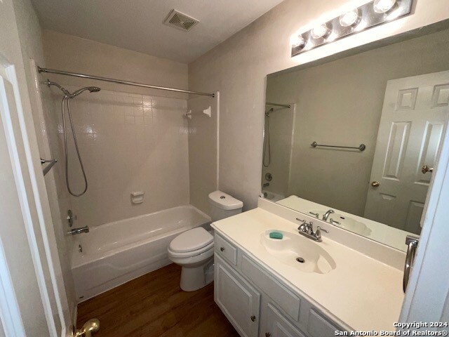 full bathroom featuring wood-type flooring, bathing tub / shower combination, vanity, and toilet