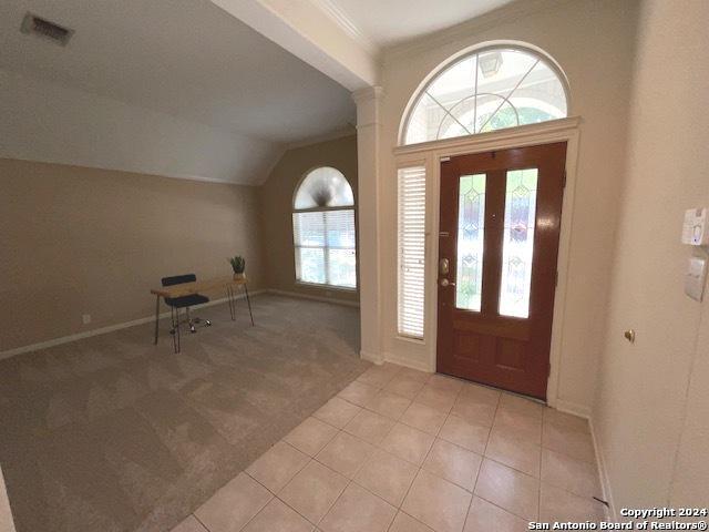 carpeted foyer entrance with lofted ceiling and crown molding