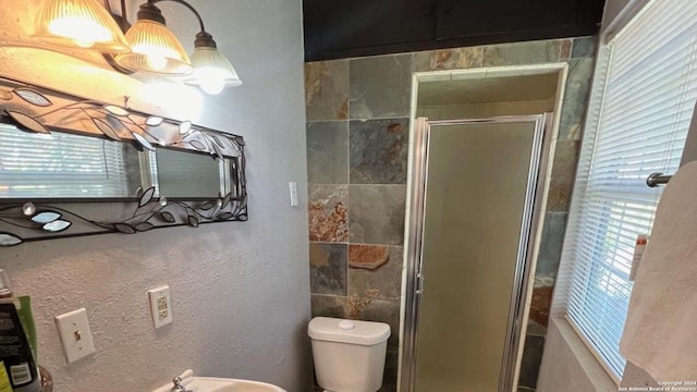 bathroom featuring a healthy amount of sunlight, an inviting chandelier, an enclosed shower, and toilet