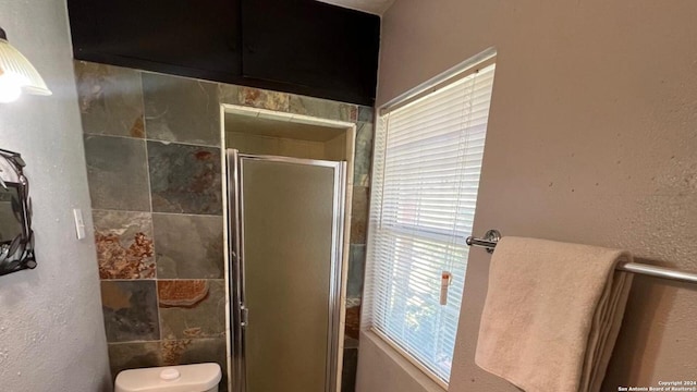 bathroom featuring toilet and a shower with shower door