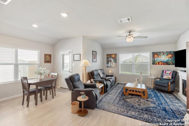 living room featuring ceiling fan, a textured ceiling, light hardwood / wood-style flooring, and vaulted ceiling