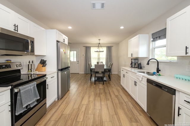 kitchen with a wealth of natural light, appliances with stainless steel finishes, and white cabinetry