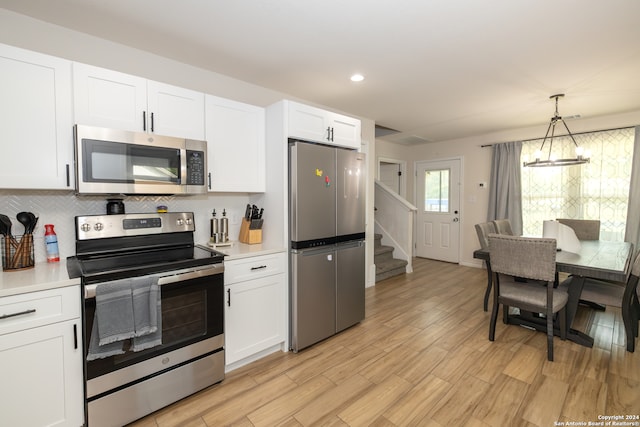 kitchen featuring pendant lighting, a chandelier, white cabinets, light hardwood / wood-style flooring, and appliances with stainless steel finishes