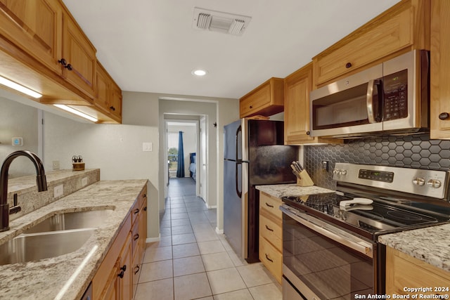 kitchen featuring light tile patterned flooring, sink, tasteful backsplash, appliances with stainless steel finishes, and light stone countertops