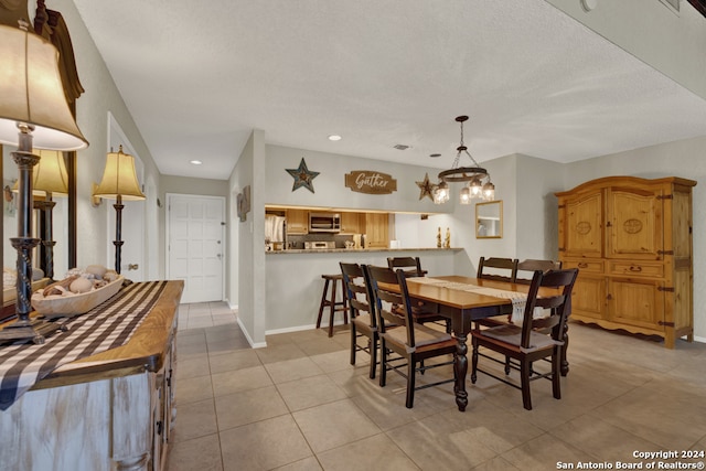 dining space featuring an inviting chandelier, a textured ceiling, and light tile patterned flooring