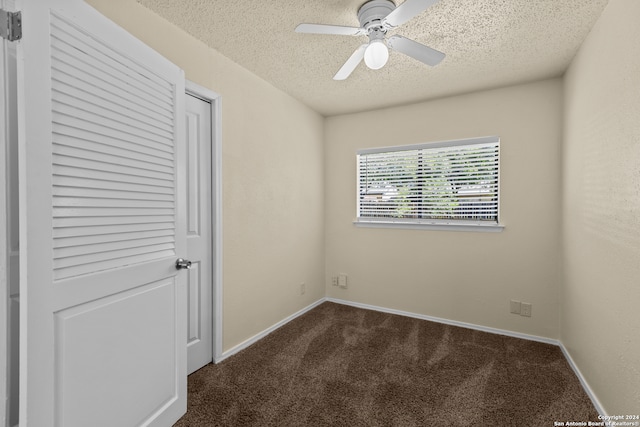 spare room with dark colored carpet, ceiling fan, and a textured ceiling