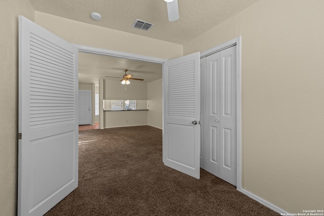 hall featuring dark colored carpet and a textured ceiling