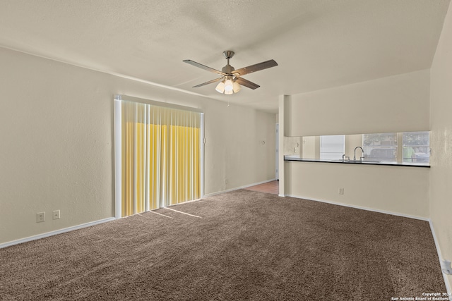 carpeted empty room with a textured ceiling, sink, and ceiling fan