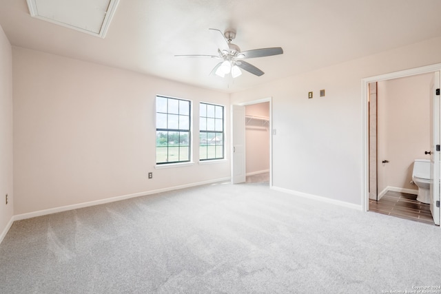 unfurnished bedroom featuring ceiling fan, connected bathroom, carpet flooring, and a spacious closet