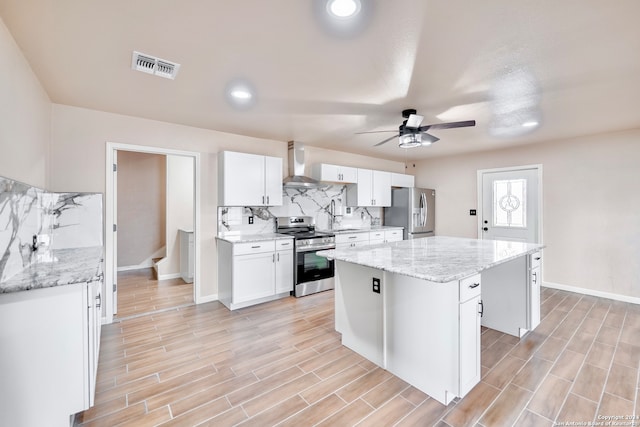 kitchen with a center island, ceiling fan, stainless steel appliances, and white cabinets