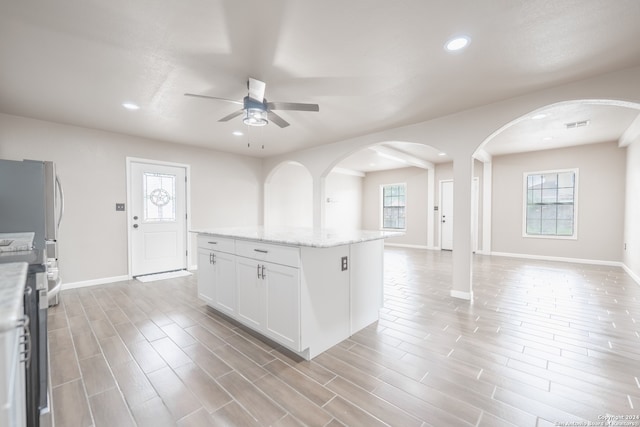 kitchen with white cabinetry, ceiling fan, plenty of natural light, and a kitchen island