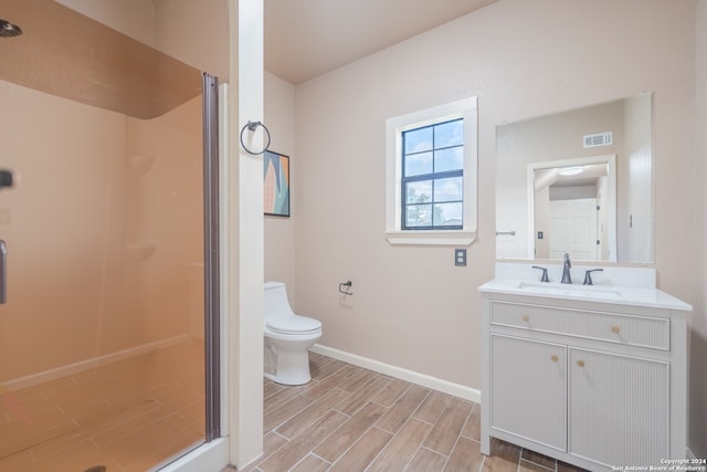 bathroom with an enclosed shower, hardwood / wood-style flooring, vanity, and toilet