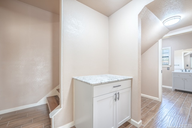 interior space with a textured ceiling, lofted ceiling, and sink