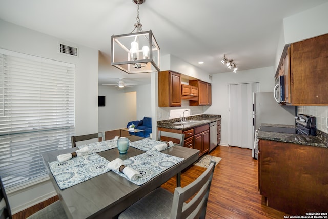 dining area with ceiling fan with notable chandelier, dark wood-type flooring, and sink