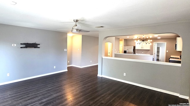 unfurnished living room featuring ceiling fan with notable chandelier and dark wood-type flooring