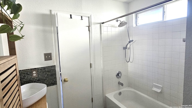 bathroom with tile walls, tiled shower / bath combo, and vanity