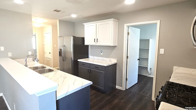 kitchen with dark wood-type flooring, black range with gas stovetop, white cabinets, stainless steel refrigerator with ice dispenser, and sink